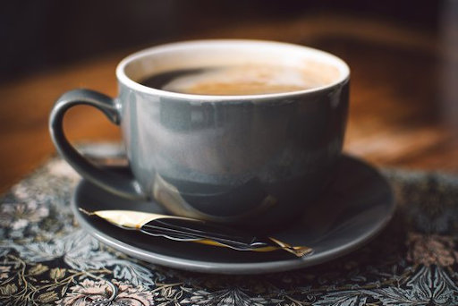 black coffee cup and saucer with a packet of coffee